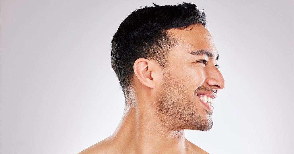 Profile of a smiling man with short dark hair against a light background.