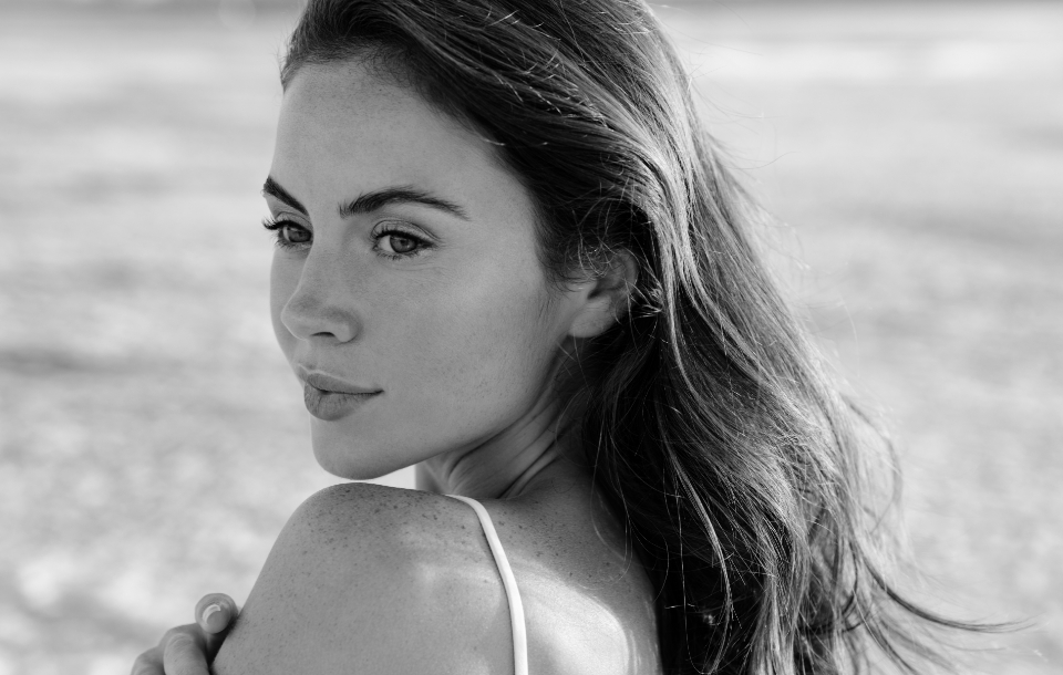 Woman with smooth, glowing skin gazing over her shoulder.
