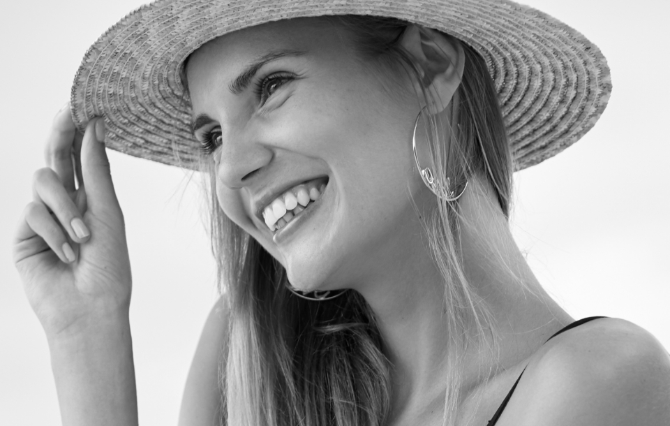 Woman wearing a straw hat and smiling brightly.