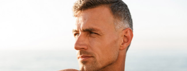 Man with gazing toward the horizon near the ocean.