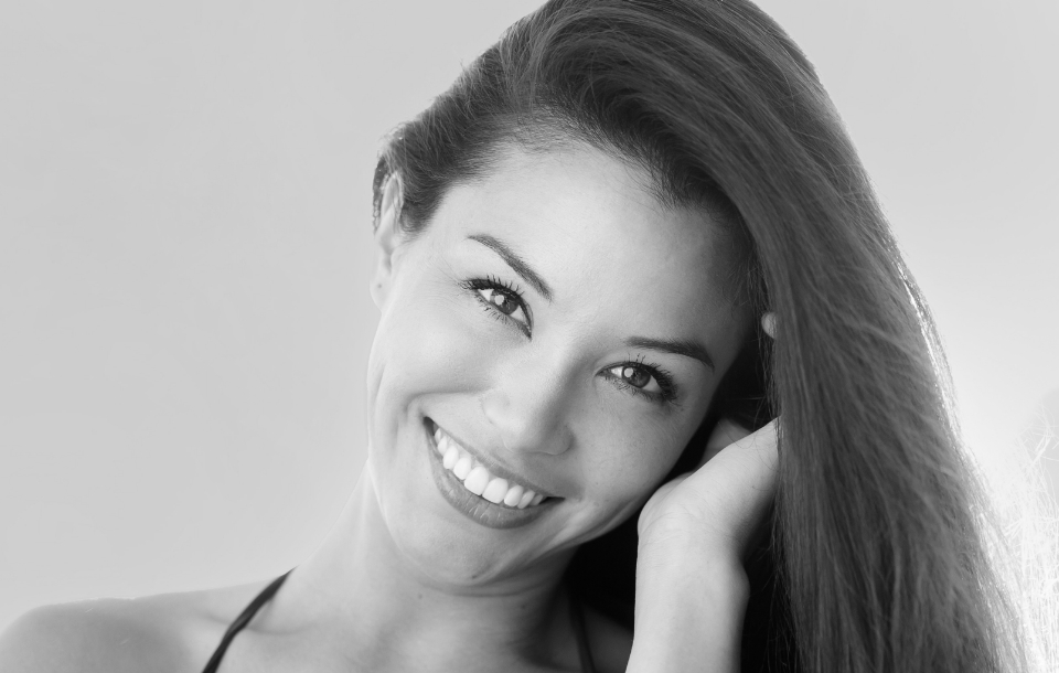 Woman with long hair smiling warmly, showing clear, glowing skin.