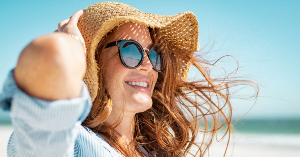 Woman smiling at the beach. (Model)